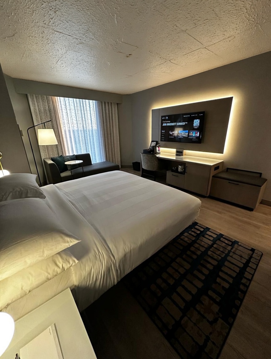 Before TrueFlat install — Marriott Greenville guestroom with aged popcorn ceiling and water staining, looking toward the TV wall